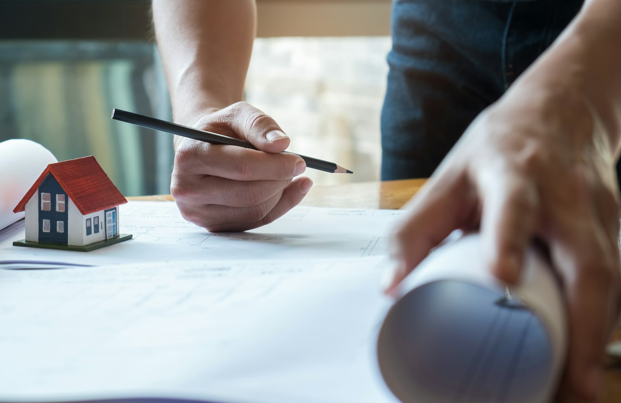 Architect has a pen and house plan in hand.