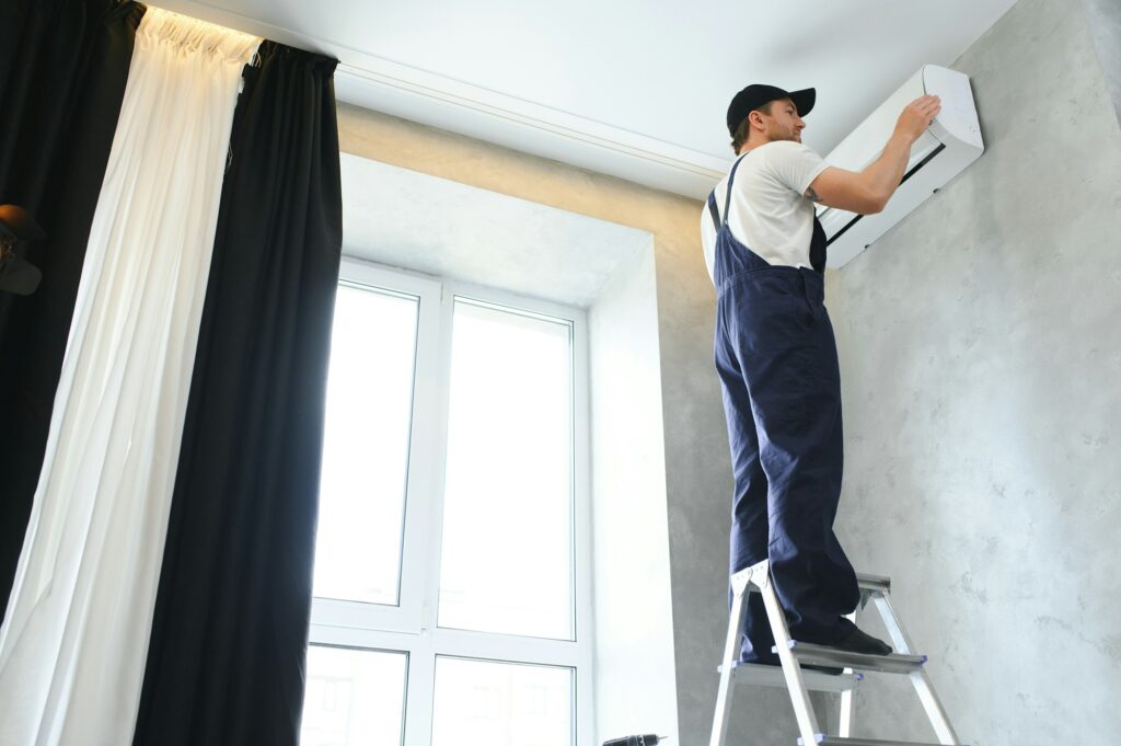 Happy Male Technician Repairing Air Conditioner.